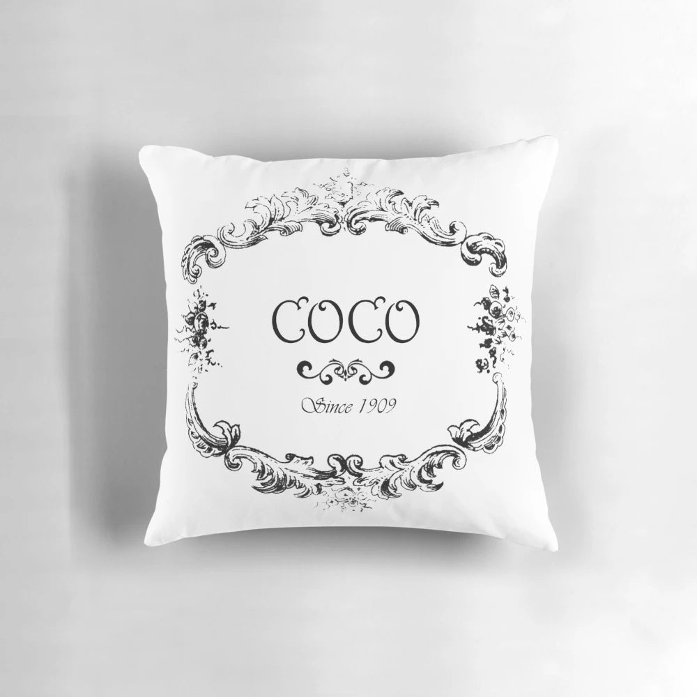 Vintage-style decorative pillow featuring a faded coco logo design in pink, turquoise, and purple