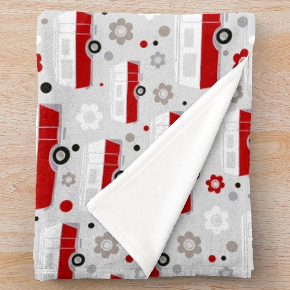 Vintage caravan-inspired plush blanket in red, white, and grey colors with a repeat pattern design