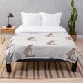 A whimsical plush blanket featuring a watercolor-style illustration of a bear on skis in a snowy, winter landscape