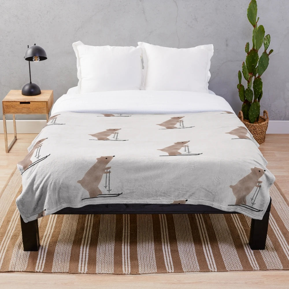 A whimsical plush blanket featuring a watercolor-style illustration of a bear on skis in a snowy, winter landscape